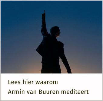 in silhouet staat Armin van Buuren met zijn linker arm omhoog, hij wijst naar de lucht